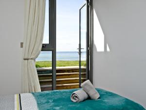 a bedroom with a bed with a view of the ocean at 4 Ocean Point in Croyde