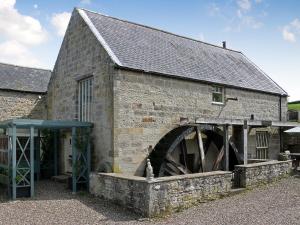 an old stone building with a wooden bridge at The Old Mill - 28218 in Thropton