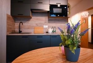 Zielone Apartamenty z aneksem kuchennym في ليجنيكا: مطبخ مع طاولة عليها إناء من الزهور