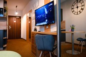 una camera con TV a parete e sedia blu di Zielone Apartamenty z aneksem kuchennym a Legnica