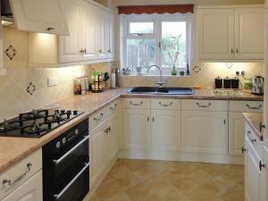 uma cozinha com armários brancos, um lavatório e um fogão em 24 Steed Close em Goodrington