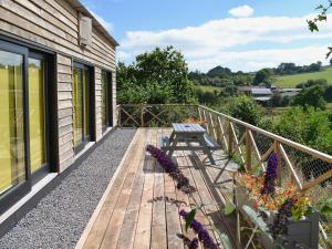 a wooden deck with a bench on the side of a house at The Shed With A View in Cadbury