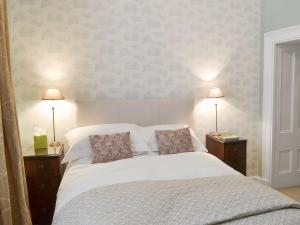 a bedroom with a white bed with two lamps at Trinity House in Ulverston