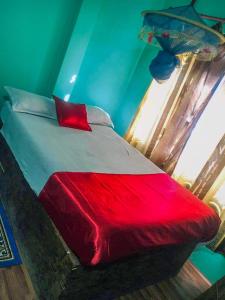 a bedroom with a bed with a red blanket at Tiger Corner Inn Homestay in Sauraha