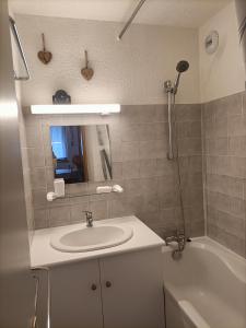 a bathroom with a sink and a tub and a mirror at Au Bord des Pistes in La Plagne