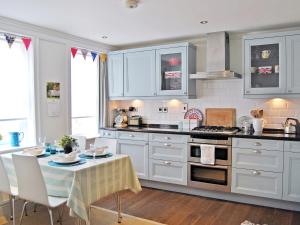 a kitchen with white cabinets and a table and a dining room at Solent Cottage - Pqqu in Yarmouth