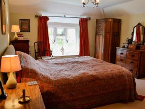 a bedroom with a bed and a window with red curtains at North Huckham in Exton
