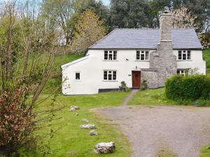 uma casa branca com uma chaminé de pedra e um quintal em North Huckham em Exton