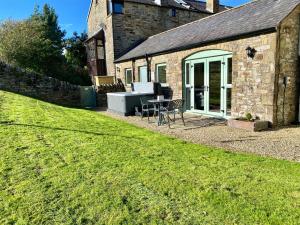 a stone house with a table and a bench in a yard at Mark Close Milking Parlour in Alston