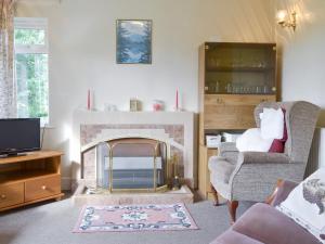 Walters Cottage في Pilton: غرفة معيشة مع موقد وتلفزيون