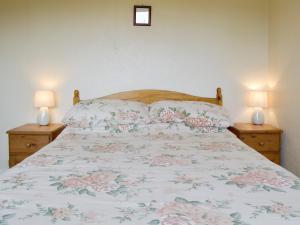 um quarto com uma cama com colcha floral e 2 candeeiros em Walters Cottage em Pilton