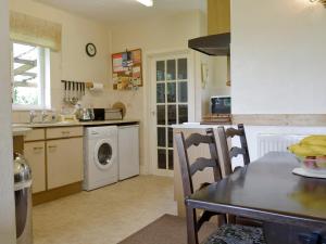 uma cozinha com uma mesa e uma máquina de lavar roupa em Walters Cottage em Pilton