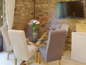 a dining room with a glass table with chairs and a television at The Garden Room - 15536 in Marldon