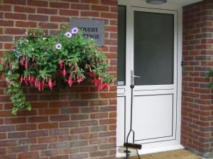 uma porta com um plantador de flores ao lado de uma parede de tijolos em Covert Cottage em Gasthorpe