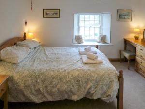 a bedroom with a bed with two towels on it at Chapel Cottage in Askham
