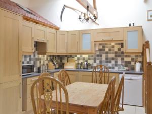 eine Küche mit einem Holztisch sowie einem Tisch und Stühlen in der Unterkunft Orchard View Barn in Plymtree