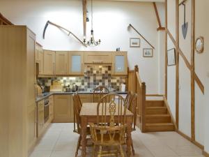 eine Küche mit einem Tisch und Stühlen sowie eine Treppe in der Unterkunft Orchard View Barn in Plymtree