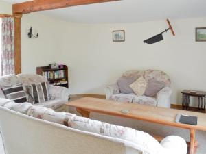 a living room with two couches and a wooden table at Orchard View Barn in Plymtree