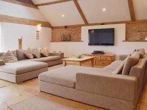 a living room with two couches and a flat screen tv at Hobland Barn in Belton