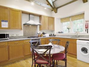 una cucina con armadi in legno, tavolo e sedie di Stables Cottage-uud a Corsock