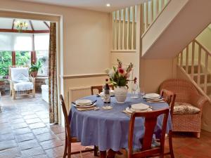 a dining room with a blue table and chairs at Oast Cottage in Herstmonceux