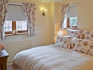 a bedroom with a white bed and two windows at Oast Cottage in Herstmonceux