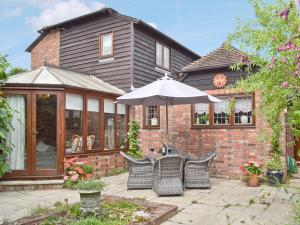 a patio with chairs and an umbrella in front of a house at Oast Cottage in Herstmonceux