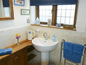 a bathroom with a white sink and a window at Oast Cottage in Herstmonceux