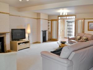 a living room with a couch and a television at Pettaugh Lodge in Debenham