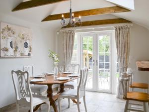 a dining room with a wooden table and chairs at Pettaugh Lodge in Debenham