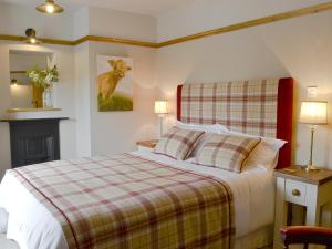 a bedroom with a bed with a plaid blanket at Pettaugh Lodge in Debenham