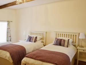 a bedroom with two beds and a chandelier at The Byres in Greenhaugh
