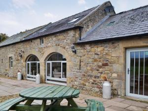 a green picnic table in front of a stone building at The Byres in Greenhaugh