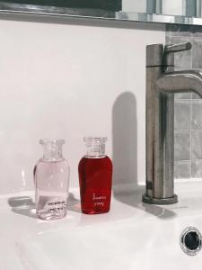 deux bouteilles en verre assises sur un évier à côté d'un robinet dans l'établissement Minds House, 