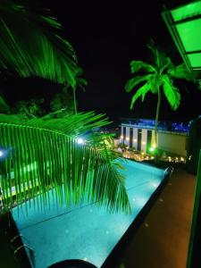 Miracle Hotel and Resorts في كوجيكود: حمام سباحة في الليل مع أضواء خضراء