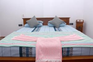a bed with two pink and blue pillows on it at Hispaniola villa in Mirissa