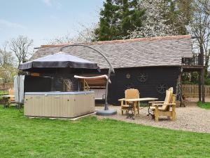 a black shed with a table and chairs and an umbrella at Byre Cottage - 29410 in Elmsted