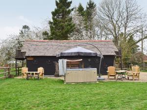 a black shed with a table and chairs in a yard at Byre Cottage - 29410 in Elmsted