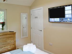 a bedroom with a flat screen tv on the wall at Dairy Cottage in Bodmin