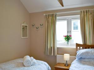 1 dormitorio con 2 camas individuales y ventana en Dairy Cottage, en Bodmin