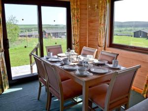 a dining room table with chairs and a table and a window at Hartland Forest Golf Leisure in Woolfardisworthy