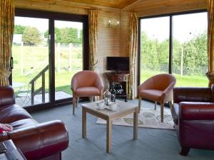 WoolfardisworthyにあるHartland Forest Golf Leisureのリビングルーム(ソファ、椅子、テーブル付)