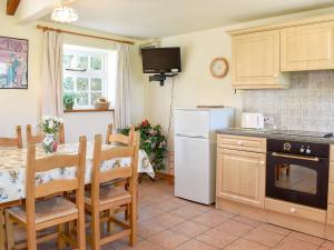 cocina con mesa y nevera blanca en Mill Pond Cottage, en Bere Regis