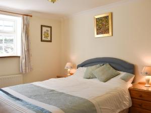 a bedroom with a bed and two lamps and a window at Mill Pond Cottage in Bere Regis