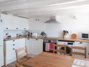 a kitchen with white cabinets and a wooden table at White Cottage in Lower Largo