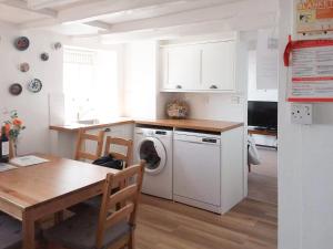 a kitchen with a washing machine and a dining room table at White Cottage in Lower Largo