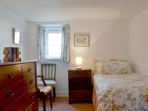 a bedroom with a bed and a dresser and a window at White Cottage in Lower Largo