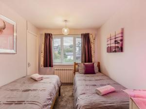 two beds in a small room with a window at Strawberries And Cream in Bowness-on-Windermere