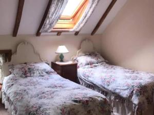 two beds in a bedroom with a window at The Oast House in Boraston