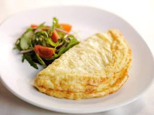a white plate with a omelet and a salad at SUBHAN PALACE Near Lasania Restaurant & Millennium Mall in Karachi